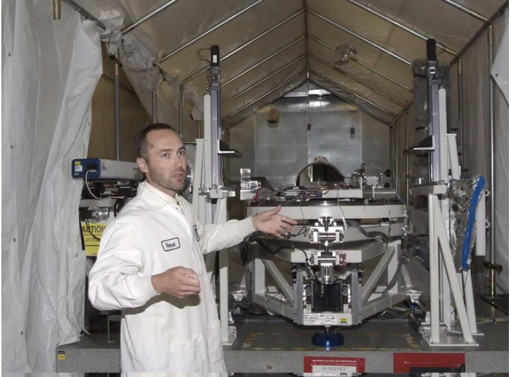Patrick Johnson is standing in front of an optical test station at Tinsley Labs used to measure mirror surfaces.