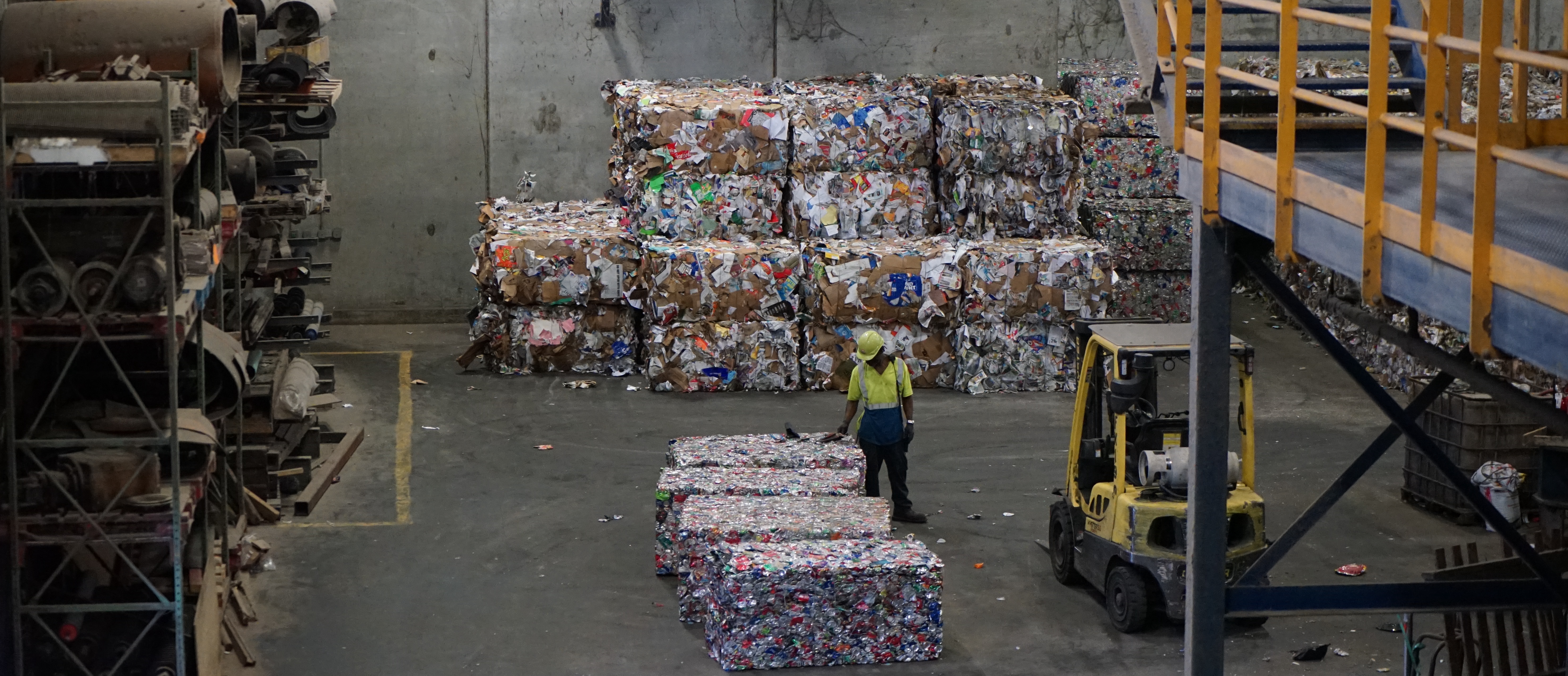 A bunch of baled materials and a worker at the recycling center